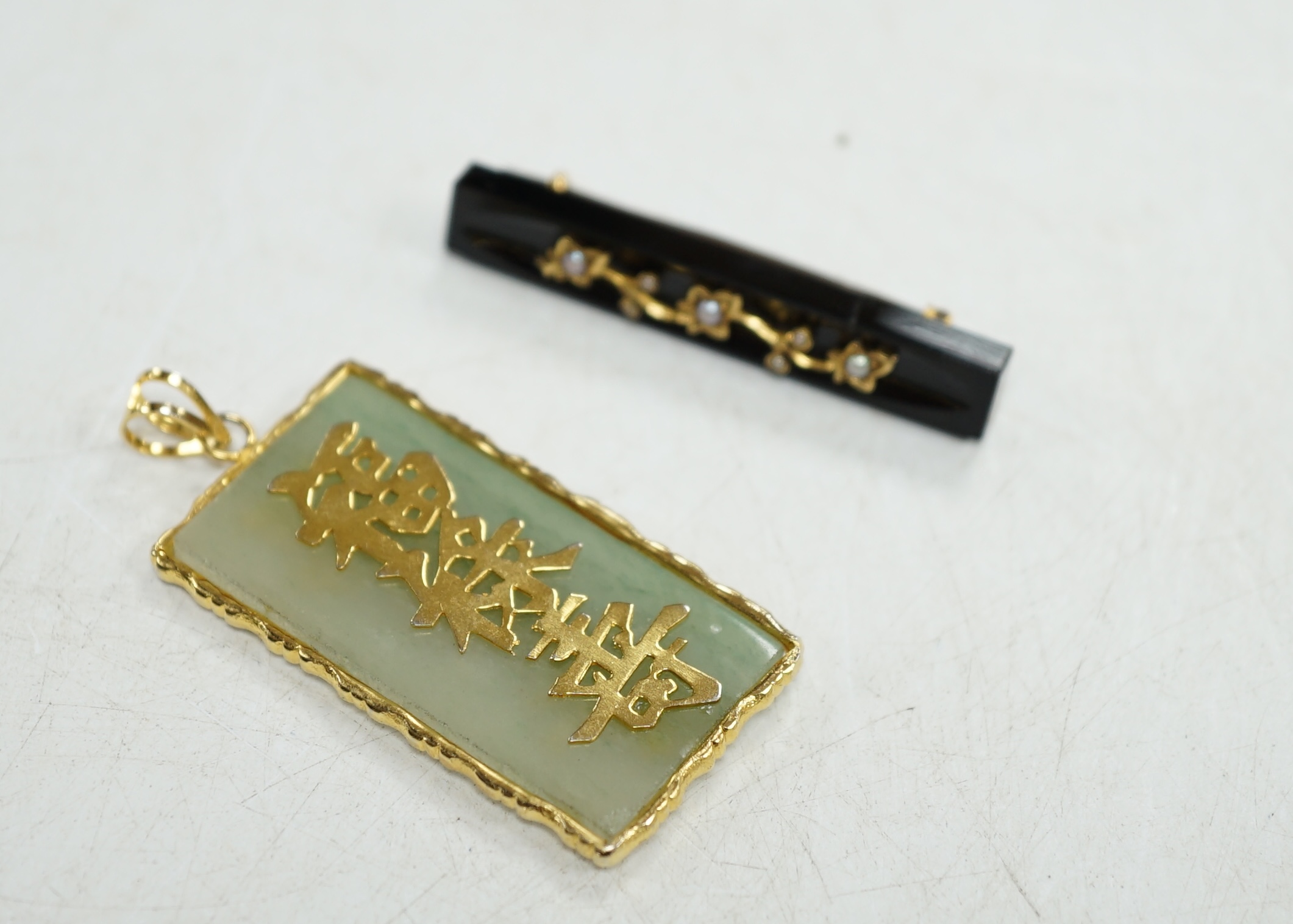 A late Victorian gold mounted black onyx and pearl bar brooch, and a Chinese yellow metal mounted jadeite pendant. Condition - fair